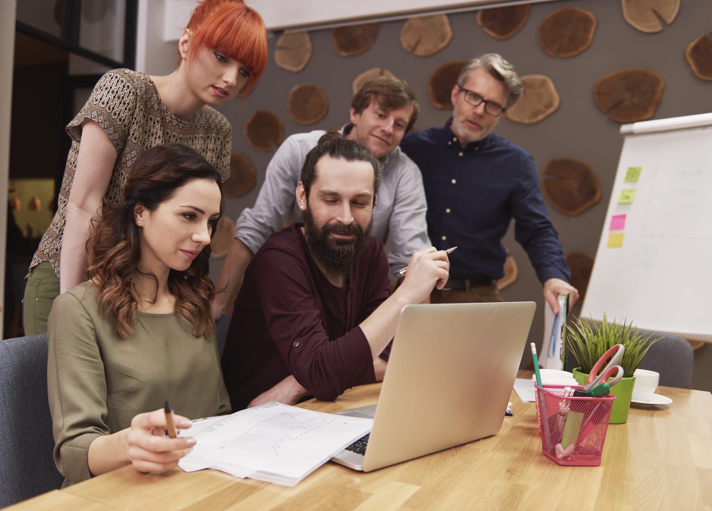Equipa a trabalhar em conjunto à volta de um computador portátil